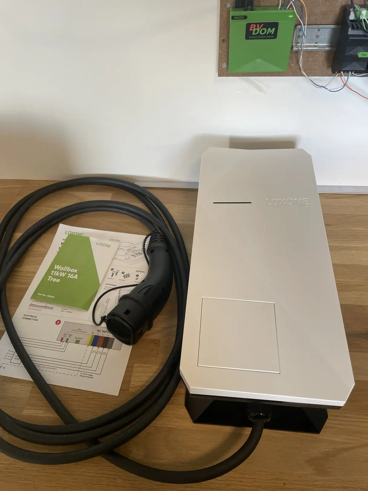 Wallbox Loxone 11 kW 16 A Tree et son câble de charge avant installation, devant un coffret BVDOM