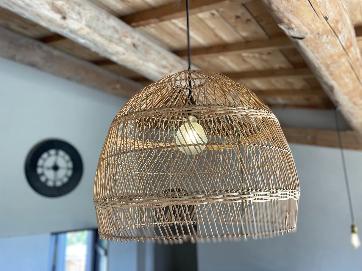 Suspension en rotin équipée d'une ampoule globe G95 24 V, sous un plafond à poutres apparentes