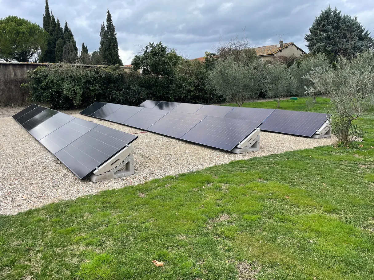 Panneaux photovoltaïques posés au sol sur supports béton dans un jardin