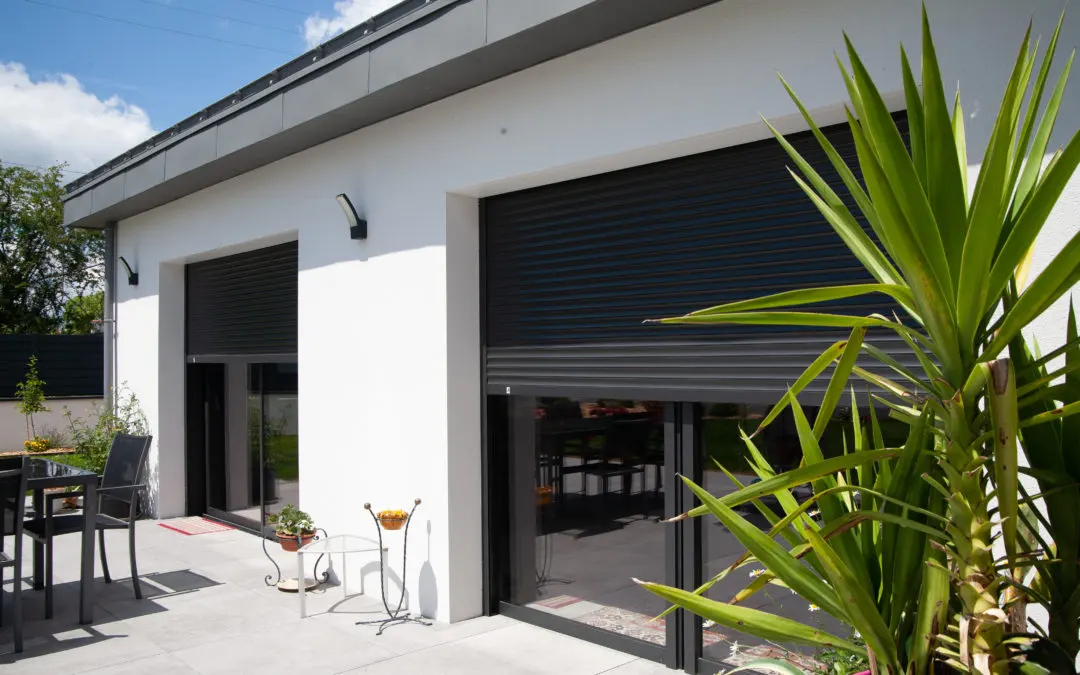 Volets roulants sombres partiellement descendus sur les baies vitrées d'une maison contemporaine