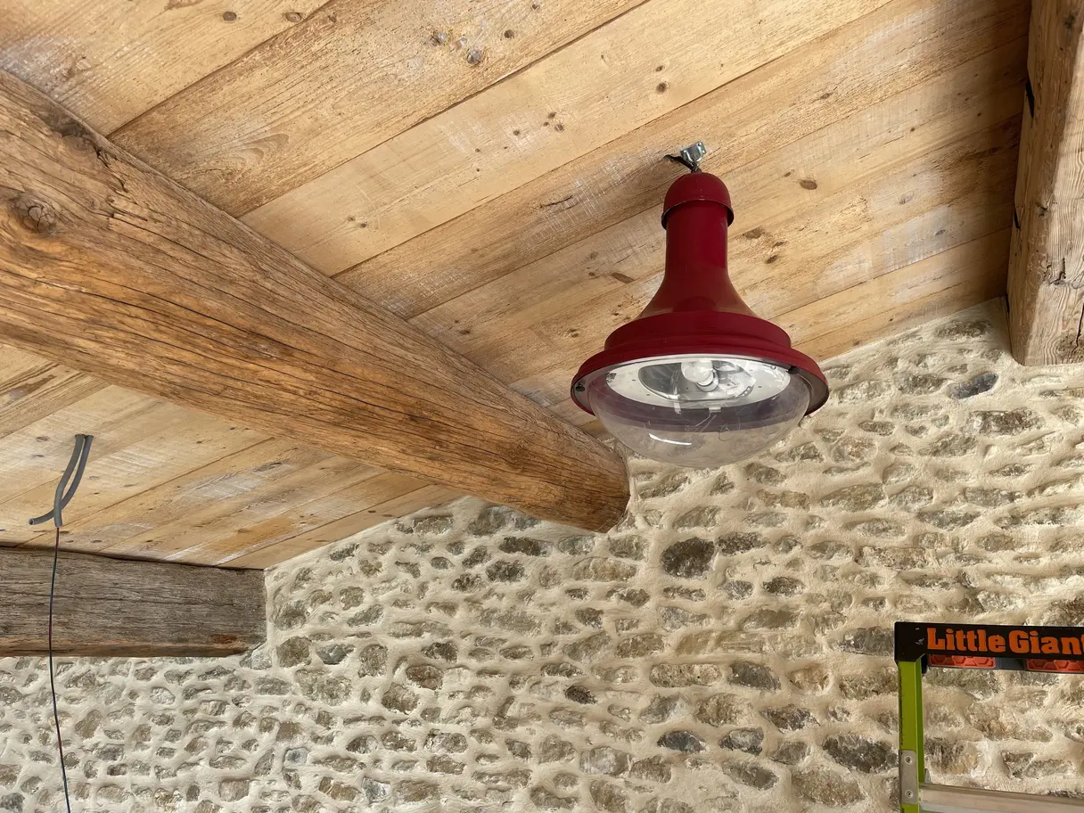 Suspension industrielle rouge fixée sur la charpente en bois du garage