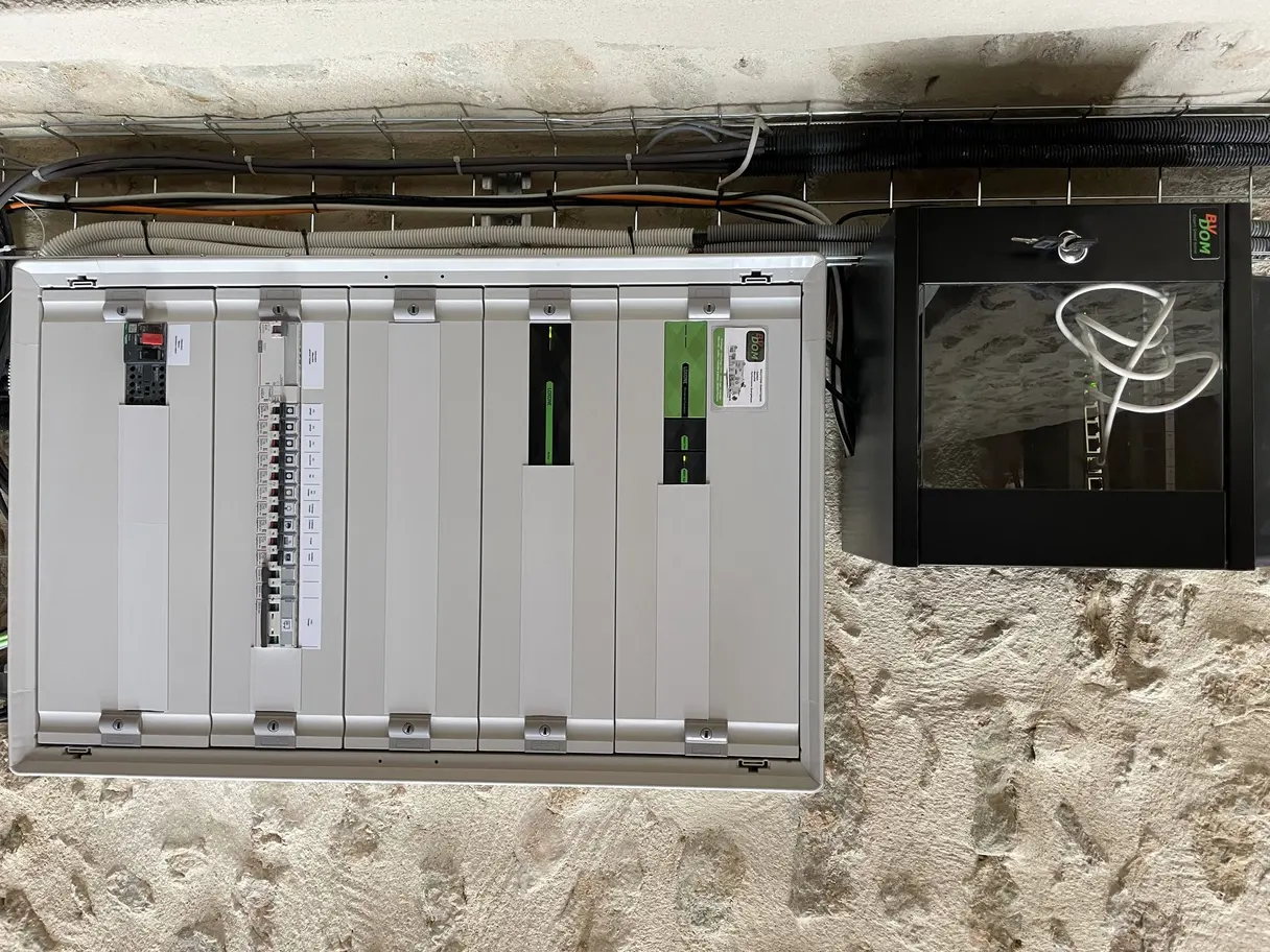 Tableau électrique Loxone du garage et coffret réseau installés sur le mur en pierre