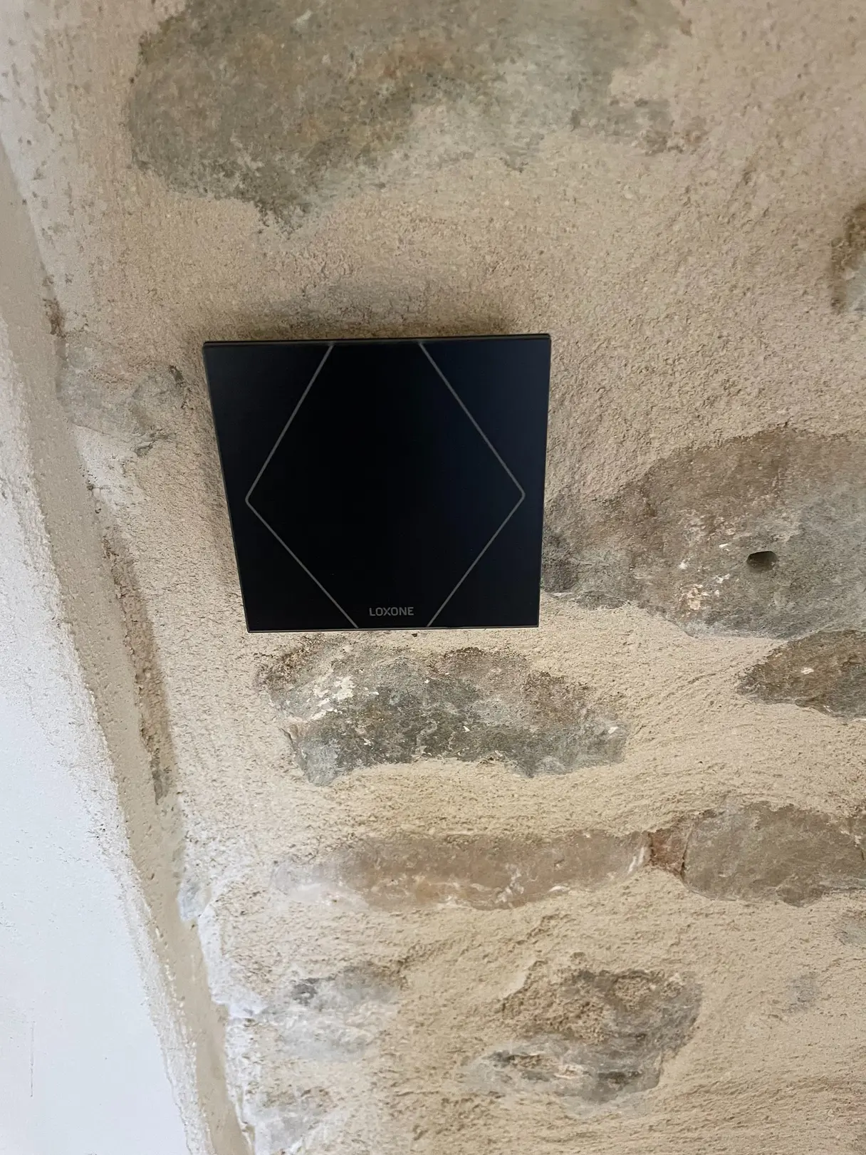 Interrupteur tactile Loxone encastré dans un mur en pierre du mas