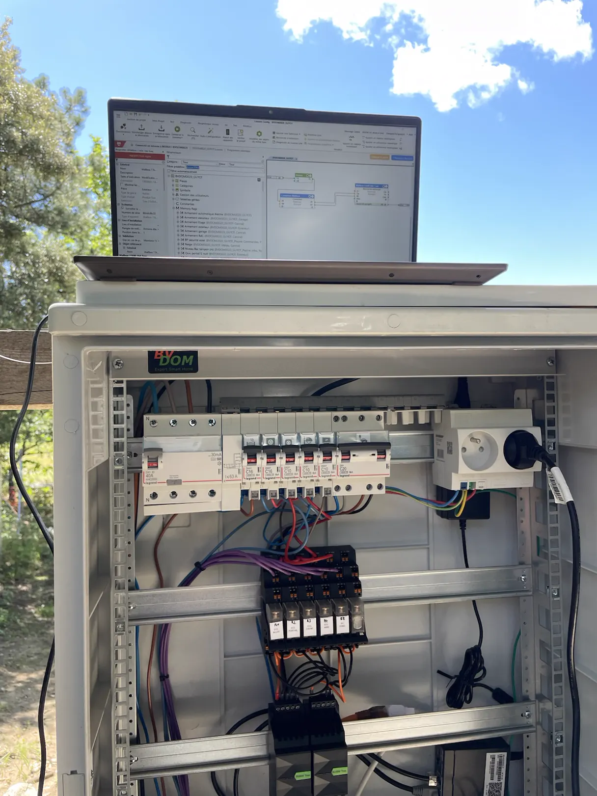 Coffret électrique extérieur BVDOM près du portail, l'ordinateur ouvert sur Loxone Config posé dessus